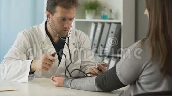 在医院诊所检查女性患者血压的中年医生视频的预览图