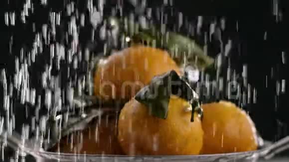 在视频中我们看到橘子它们是折叠的水从顶部落下黑色的背景视频的预览图