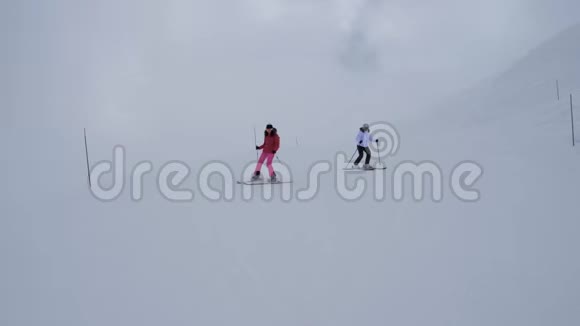 冬季两名女子滑雪者在山腰上同步滑雪视频的预览图