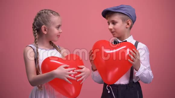 恋爱中的快乐孩子手里拿着红色心形气球对着镜头微笑视频的预览图