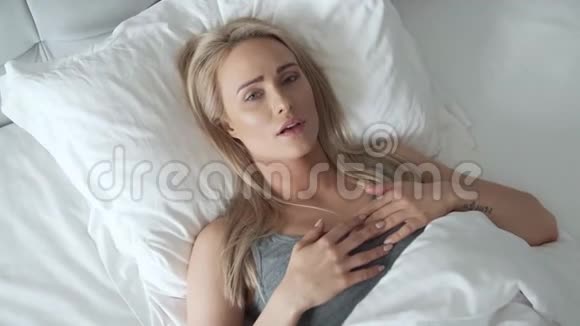 坐在床上抱着头的女人她头痛得很痛视频的预览图