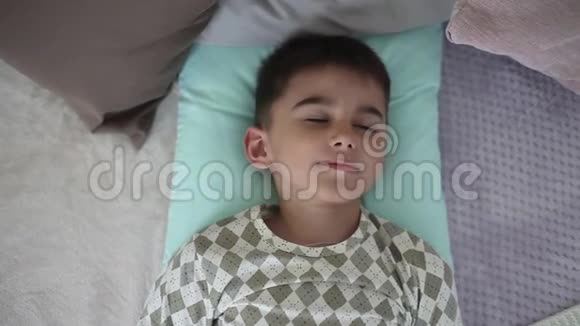 小男孩醒来躺在有枕头的床上视频的预览图