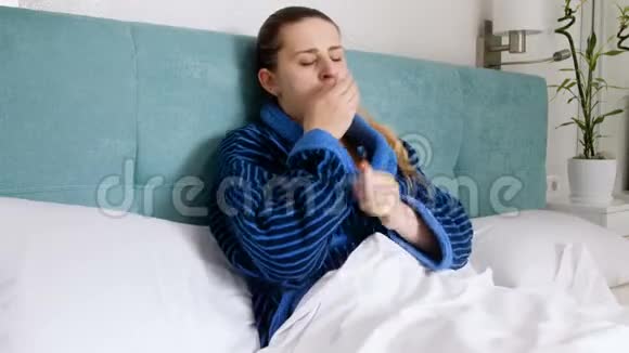 4k视频咳嗽年轻女子感到恶心躺在床上拿着体温计视频的预览图