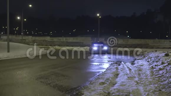 夜晚车停在空无一人的雪道上车前灯开着行动孤独的车霓虹灯站着视频的预览图
