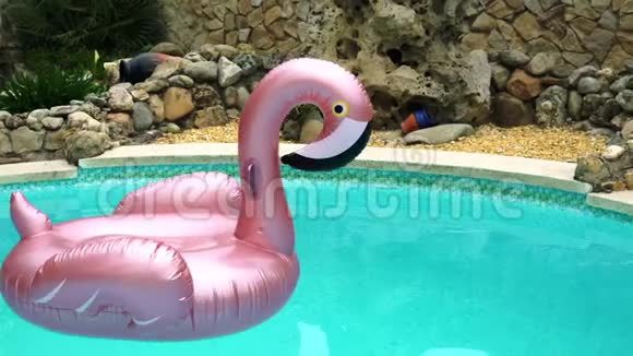 闪闪发光的火烈鸟橡胶圈在雨滴中漂浮在游泳池里视频的预览图