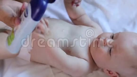 妈妈做新生儿宝宝按摩在身体上涂油特写视频的预览图