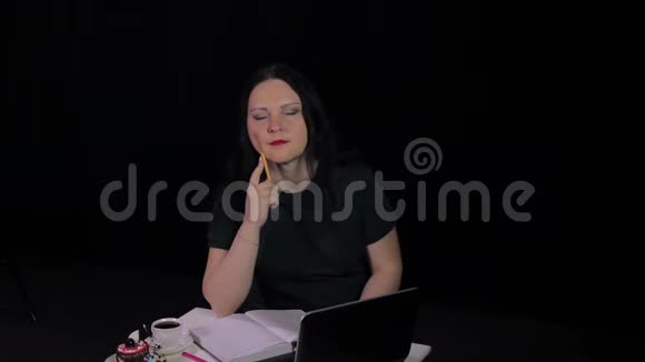 在咖啡馆的一张桌子上一个忧郁的女人在电脑上工作喝咖啡视频的预览图
