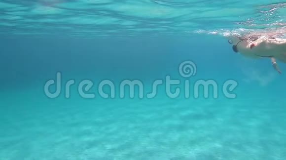 一个穿着黑色比基尼的年轻美女带着面具和浮潜在蓝色的水里游泳动作缓慢视频的预览图