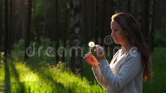 女人在蒲公英种子头上触摸手指花吹着小花飞走了视频的预览图