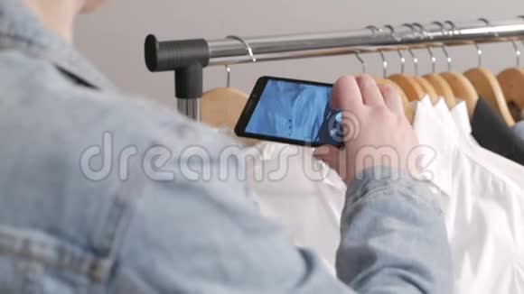 一个女人用智能手机检查和拍照一件挂在衣架上的东西视频的预览图