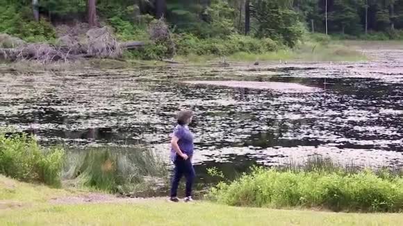 年轻的成年女人在湖边散步视频的预览图
