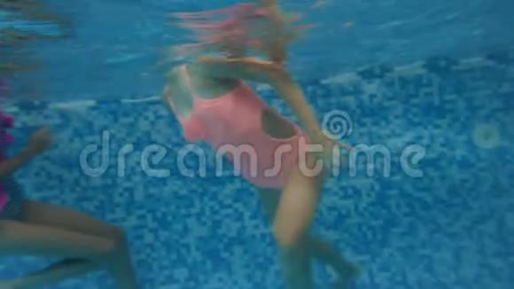 两名身穿泳装的少女在室内游泳池水下潜水的4k水下镜头视频的预览图