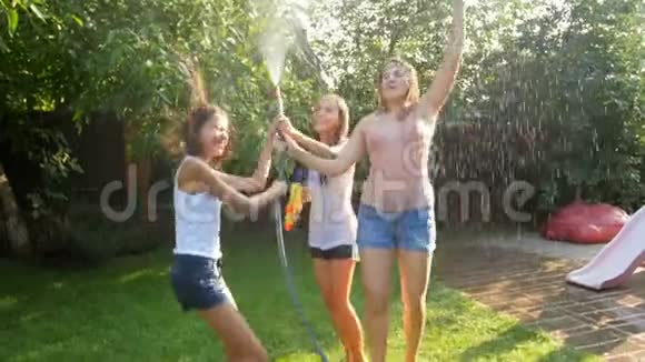 在炎热的晴天三个笑女在花园水管里的水中跳舞视频的预览图