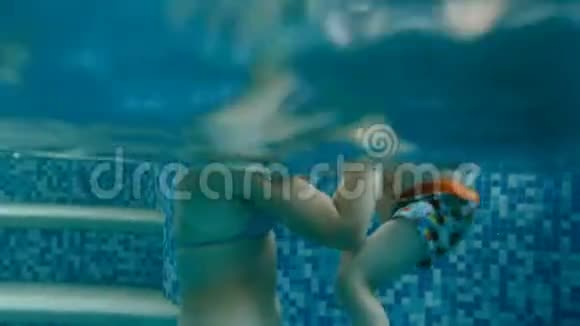 水下视频年轻的欧文教她的孩子在酒店的室内游泳池游泳视频的预览图