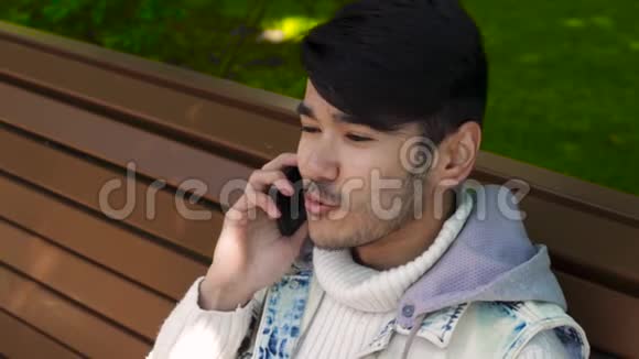 微笑的亚洲男人通过电话交谈视频的预览图