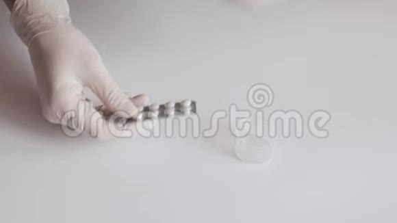 一位戴着白色乳胶手套的护士将药片从白色桌子上的水泡里挤出来视频的预览图
