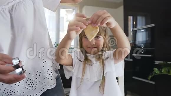 一个小女孩的肖像她拿着面团看着她和母亲做的饼干视频的预览图