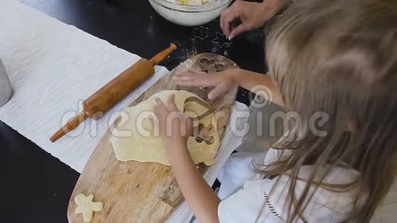 最高的视野穿着白色连衣裙的长发小女孩在家里的厨房里做姜饼饼干用面团孩子视频的预览图
