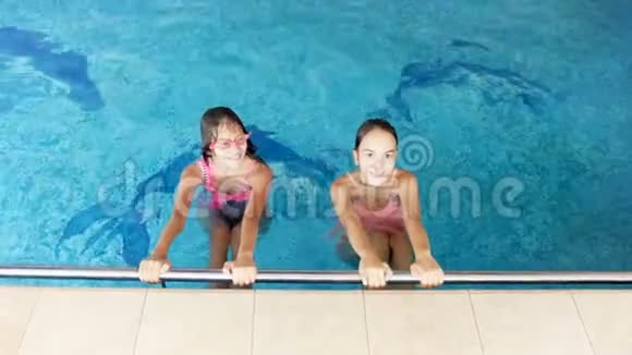 4k视频两个微笑的少女抱着泳池边看镜头视频的预览图
