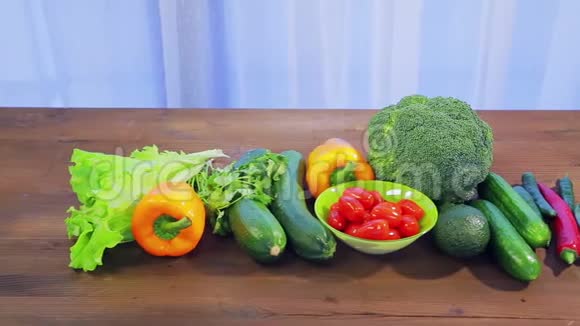 木桌上有新鲜蔬菜西葫芦西兰花生菜鳄梨黄瓜胡椒和辣椒樱桃番茄视频的预览图