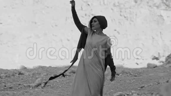 女孩正在岩石附近的沙漠里跳舞黑白图像视频的预览图