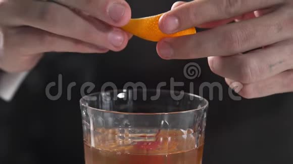 酒保在酒吧的酒精饮料中加入橙皮在酒吧里制作鸡尾酒酒精饮料酒精视频的预览图