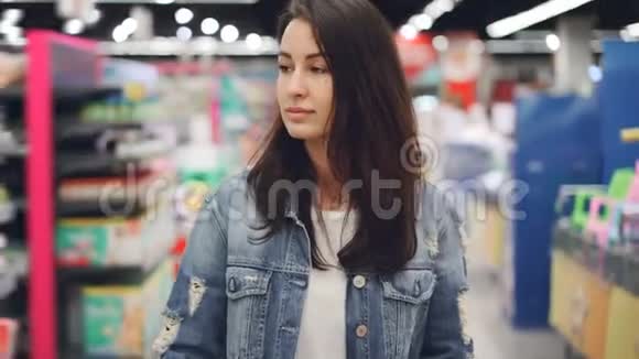 漂亮的女士正穿过超市的过道购物车里放着明亮的商品购物视频的预览图