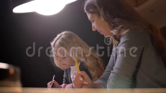 年轻的白种人母亲在家教她漂亮的小女儿的特写镜头视频的预览图