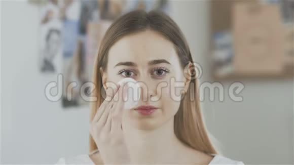美丽的女人用棉垫洗脸看着相机视频的预览图