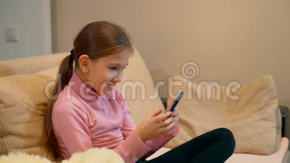 一个10岁的女孩正在智能手机上玩手机游戏视频的预览图