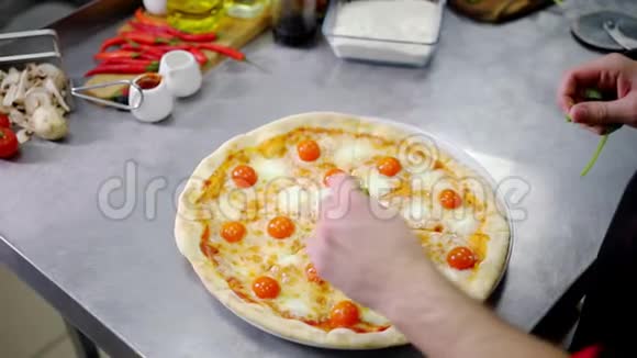 餐厅厨房一位厨师用绿色装饰披萨视频的预览图