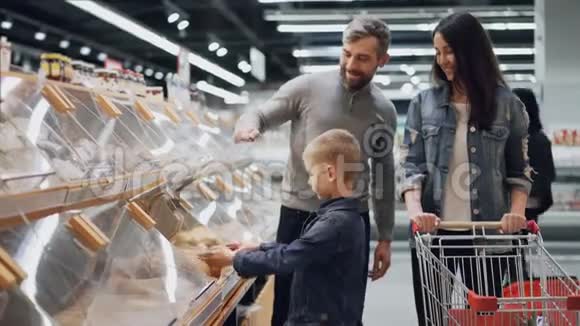 可爱的小男孩正在帮助他的父母在食品店的面包店选择面包他正在拿面包和视频的预览图