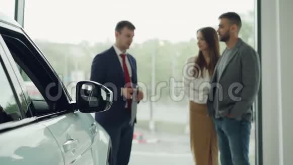 专业的汽车销售商正在和富有魅力的夫妇交谈告诉他们新车视频的预览图