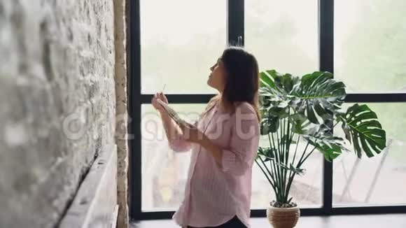 创意女性正在装修她的阁楼风格公寓在砖墙上选择美丽的图片和标记的位置视频的预览图