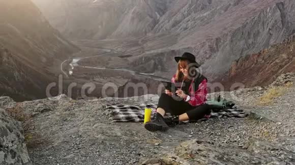 女徒步旅行者在山顶悬崖上使用数码平板电脑视频的预览图
