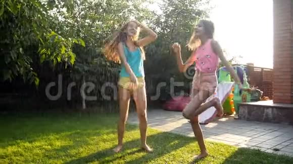 两个快乐欢笑的少女在家后院的雨中跳着舞视频的预览图
