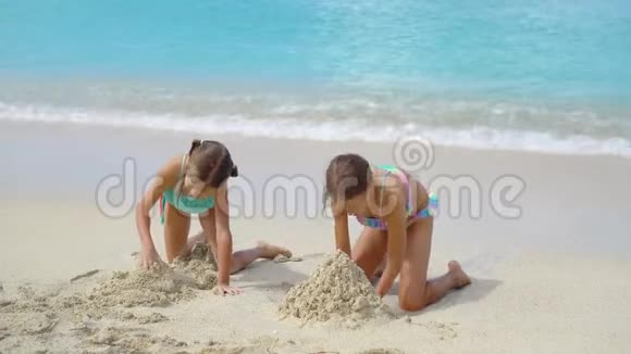 两个快乐的小女孩在热带海滩上玩得很开心一起在浅水里玩孩子们泼水视频的预览图