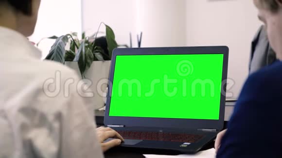 查看员工和绿色笔记本电脑屏幕从后面的办公室工作人员的笔记本电脑与绿色屏幕概念视频的预览图