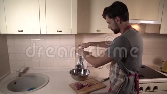 他站在厨房手拿绞肉机他把一些肉放在管子里然后再加入一些视频的预览图