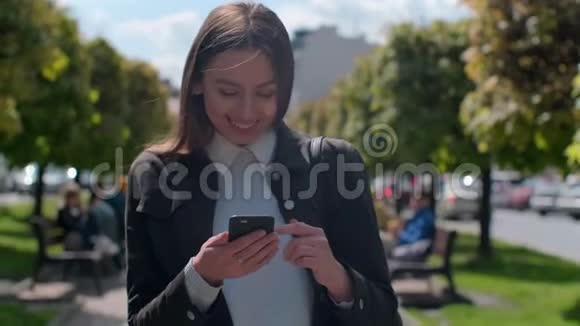 迷人的年轻女子在阳光明媚的城市街头散步和朋友聊天快乐的时髦女孩用手机视频的预览图