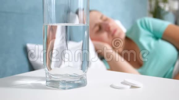慢镜头拍摄的画面显示一杯水站在床头柜上旁边躺着一位年轻女士她患有视频的预览图