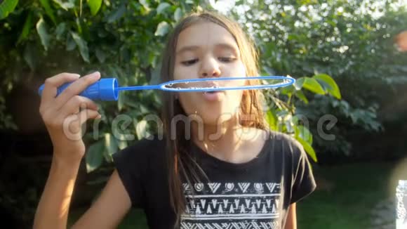 公园阳光明媚的夏日微笑的少女在镜头中吹着五颜六色的肥皂泡的慢动作视频视频的预览图