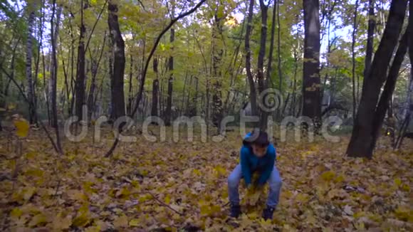 少年男孩在公园里扔黄色的秋叶慢动作视频的预览图