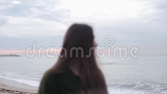 一个美丽的女孩在日出的天空和大海的背景下向旁边看女孩转过头来视频的预览图