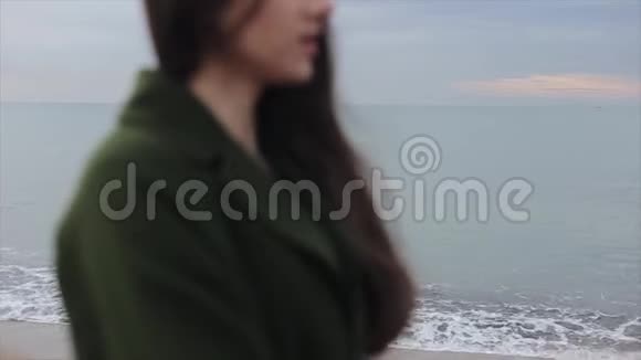 一个黑发少女在黎明时欣赏海景的模糊侧景重点转向视频的预览图