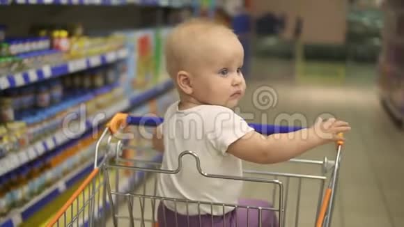 小宝宝坐在超市的购物车里等妈妈买东西回来家庭视频的预览图
