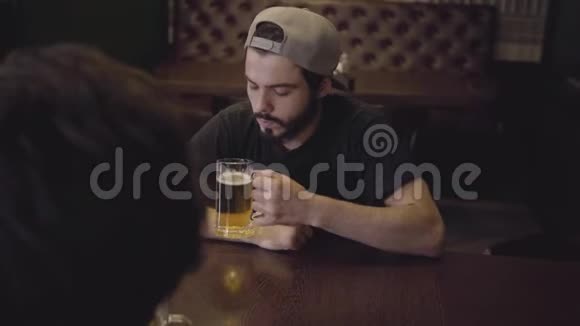 两个男人在酒吧的一张桌子旁喝啤酒一起玩得开心视频的预览图