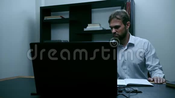 大胡子商人坐在办公室的笔记本电脑前男工想了又惊慢动作视频的预览图