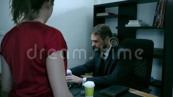 胡子商人坐在办公室的笔记本电脑前穿红衣服的女孩正试图勾引老板动作缓慢视频的预览图