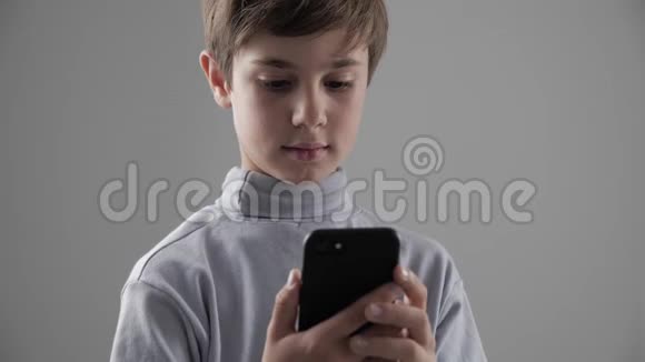 在白色背景下使用智能手机的幼童肖像男孩在智能手机上编织游戏视频的预览图